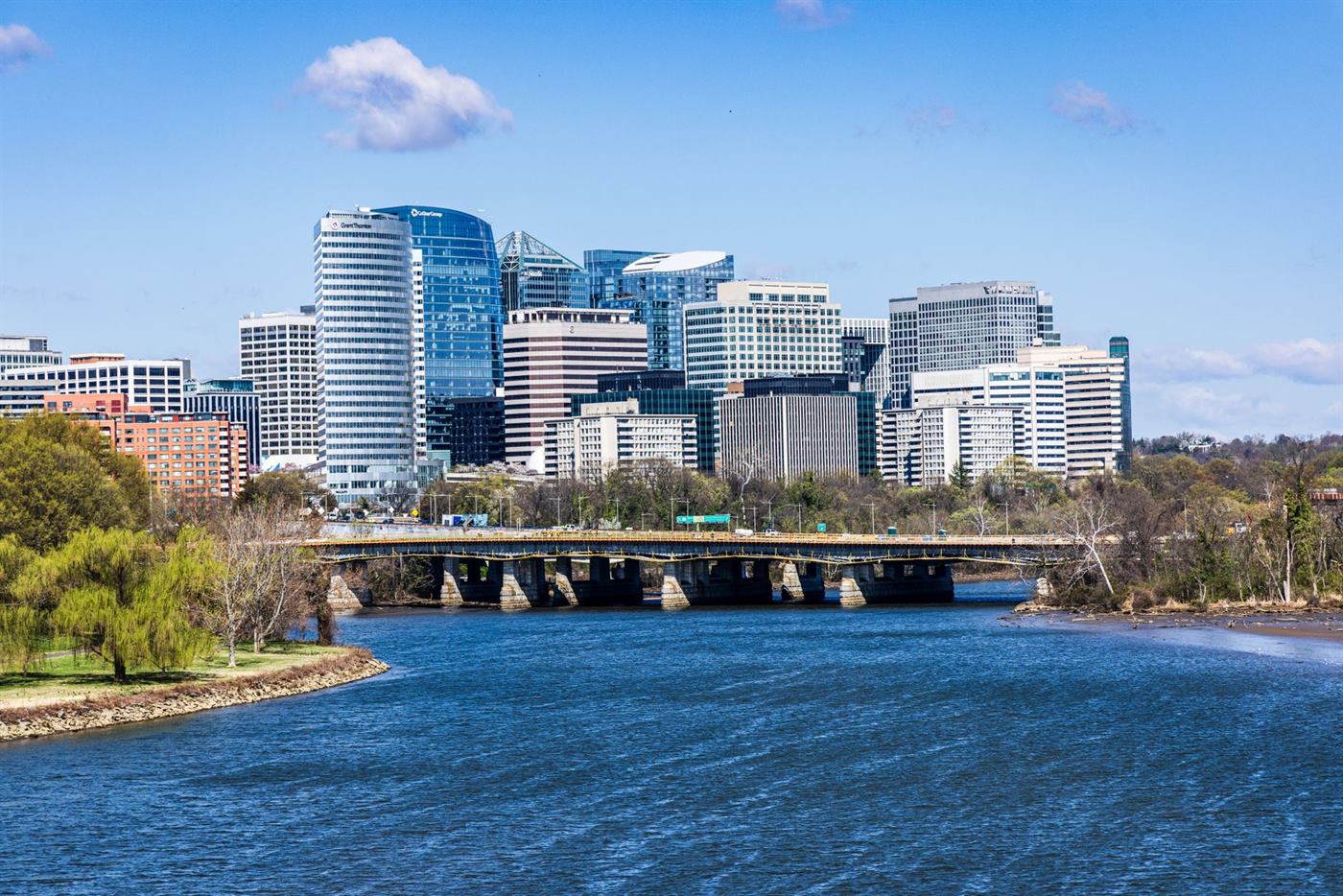 The Rosslyn skyline in Arlington, Virginia seen across the Potomac River with a bridge in the foreground